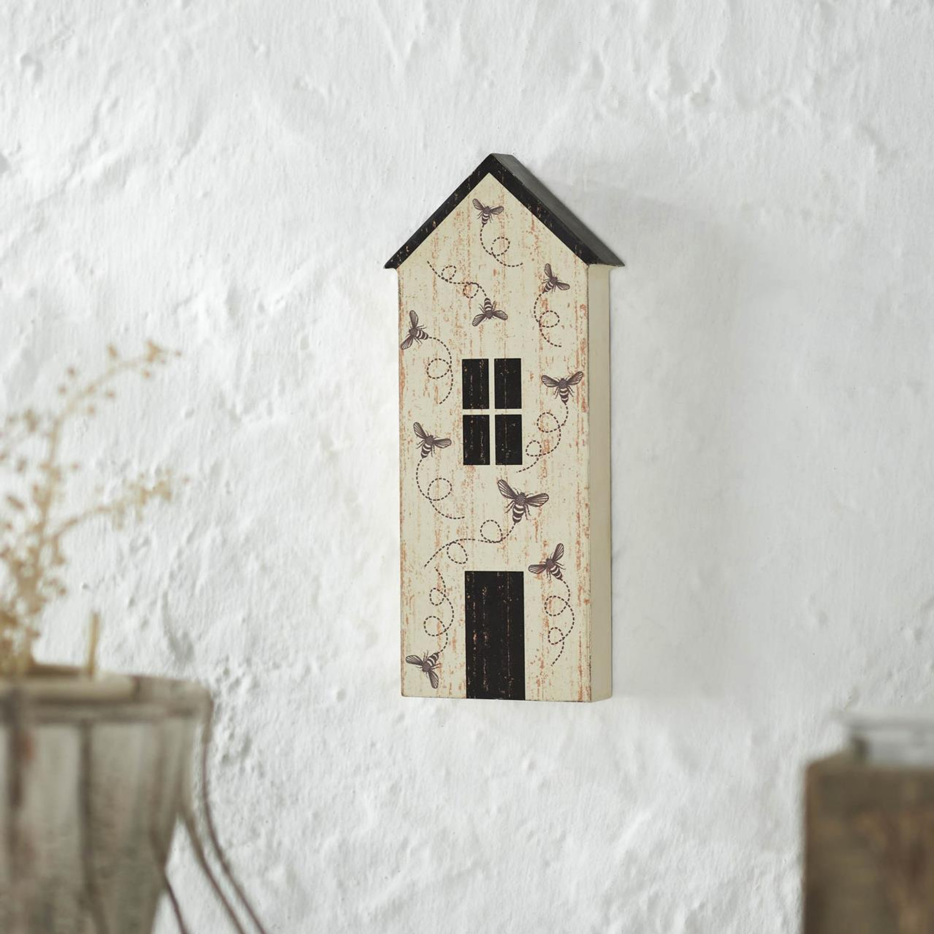 Bee house sign hanging on a white wall