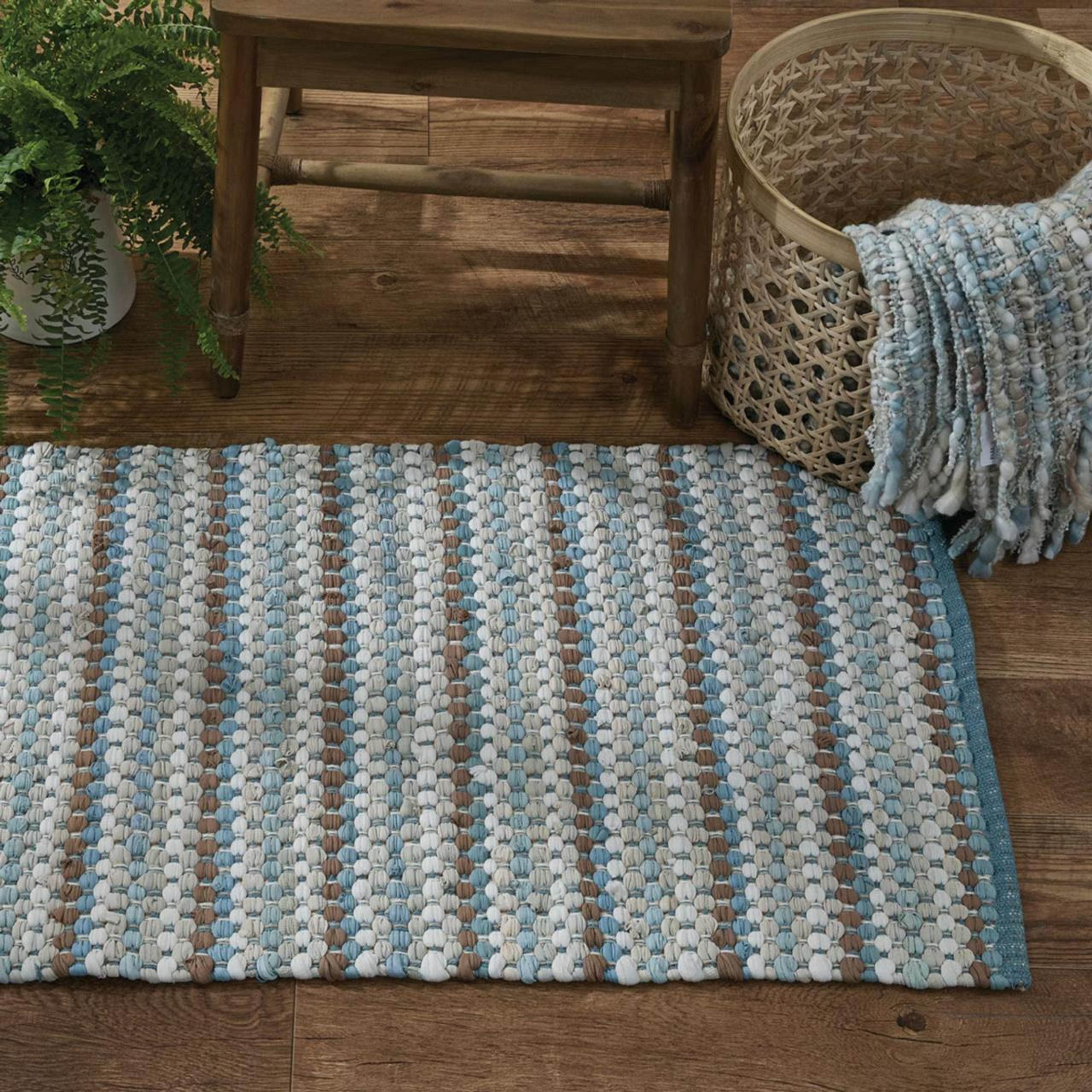 Blue and brown woven rug next to a chair and basket